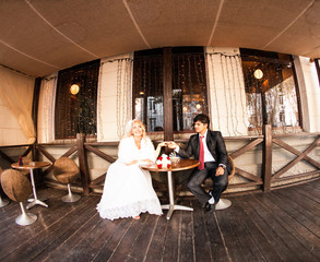 Bride and groom drinking coffee at an outdoor cafe