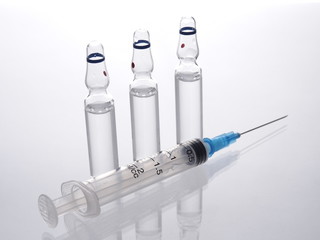Group of ampoules and injection syringe on a white background. 