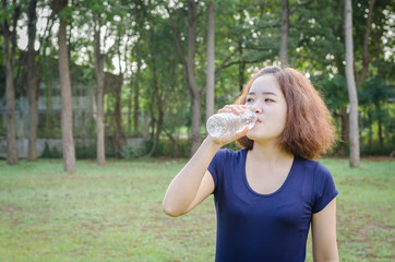 Asian woman drinking water from bottle after excercise