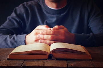 low key image of person sitting next to prayer book
