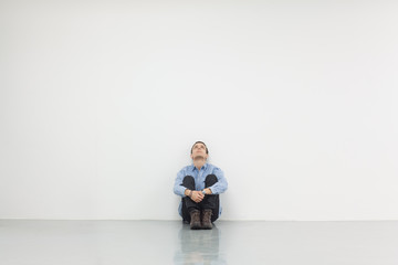 Man sitting in front of a white wall, concept of thinking