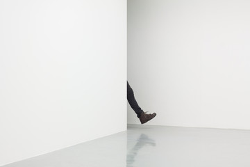 human leg in white room walking from behind corner