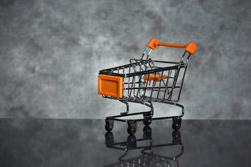 Shopping concept with an empty shopping cart in the spotlight on a dark background