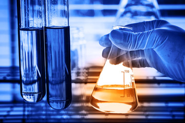 Flask in scientist hand with lab background 