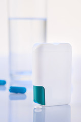 Pill dispenser and glass of water on the surface.