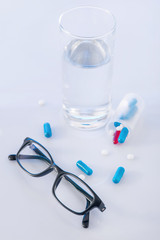 Water glass, pills and eyeglasses on the surface. 