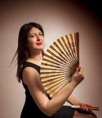 Cute woman with chinese fan. Studio.