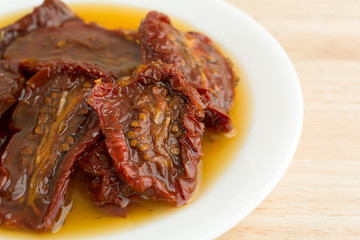 Sun dried tomatoes with olive oil on white plate