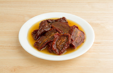 Sun dried tomatoes with olive oil on white plate