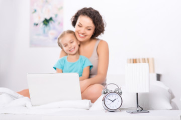 Mom and daughter in the bedroom with laptop. 