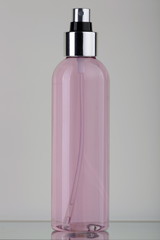 Flacone in plastica trasparente con liquido rosa e spruzzatore cromato