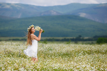 Beautiful young woman in a field of blooming daisies