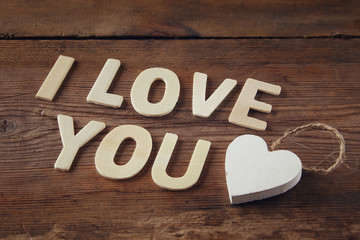 selective focus photo of The words "i love you" made with block wooden letters on wooden background.  valentine's day celebration concept. vintage filtered and toned