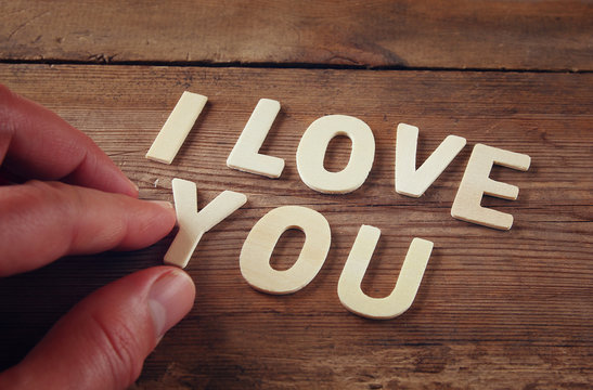 selective focus photo of The words "i love you" made with block wooden letters on wooden background. valentine's day celebration concept. vintage filtered and toned