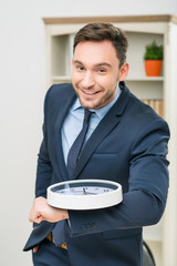 Pleasant office worker holding clock 