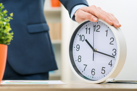Pleasant office worker holding clock 