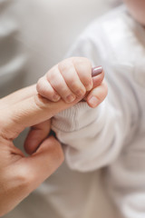 Newborn baby holding mother's finger