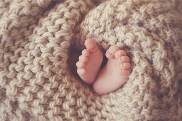 Little feet a newborn baby in a beige blanket