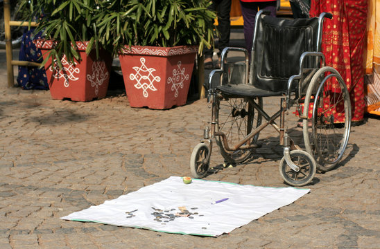 Indian Handicapped man places a wheelchair in a public place to sit on and seek alms
