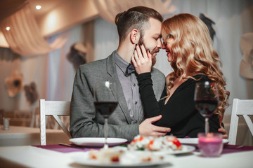 Beautiful young couple with glasses of red wine in luxury restaurant