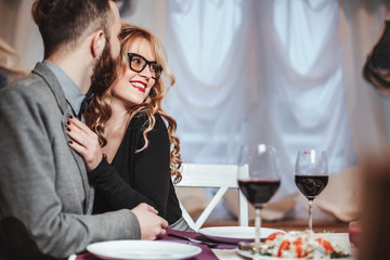 Beautiful young couple with glasses of red wine in luxury restaurant