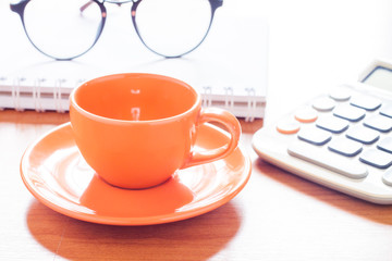Close up of coffee cup with book and eyeglasses