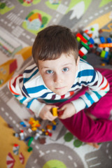 Little kid boy playing with lots of colorful plastic blocks indoor. Child having fun with building and creating