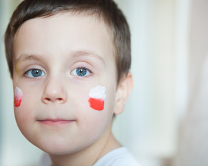boy in white shirt with polish flag on his cheeks