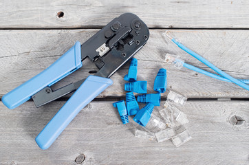 Crimping tool with network cable and connectors on wooden table