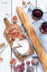 Fotobehang Picknick Camembert kaas, prosciutto (italiaanse ham), stokbrood, twee glazen rode wijn, vijgen en druiven. Witte houten tafel als achtergrond. Romantisch Frans picknicklandschap van bovenaf vastgelegd (bovenaanzicht).