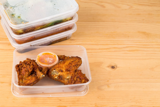 Convenient but unhealthy disposable plastic lunch boxes with take away meal on wooden table