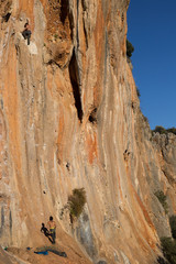 Young male climber hanging by a cliff.