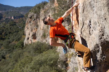Obraz premium Young male climber hanging by a cliff.