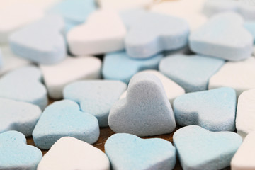 Blue and white sugar hearts spread out on flat surface
