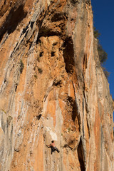 Young male climber hanging by a cliff.
