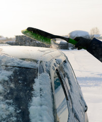 Young man cleans snow from car