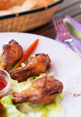 Grilled chicken wings with ketchup and greens.