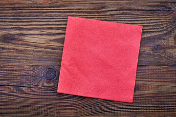 Red paper napkin on wooden table, top view