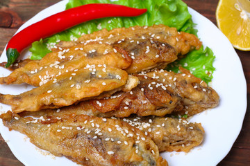 closeup of a plate with spanish boquerones fritos, battered and fried anchovies typical in Spain, on a rustic wooden table