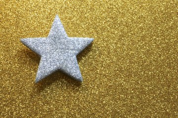 Fototapeta na wymiar silver five-pointed star in the glittering golden background