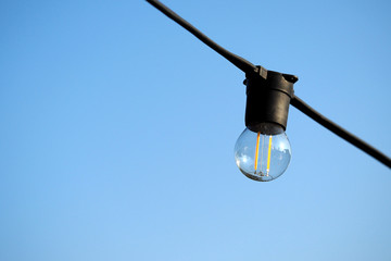 Light bulbs hanging on a electricity wire in clear blue sky background