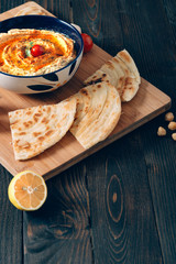 Homemade hummus with pita bread on a dark table.