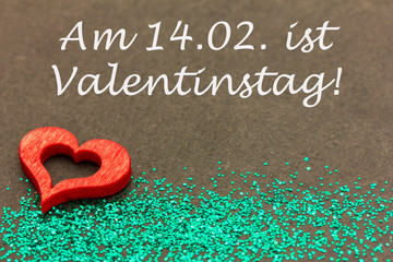 ein rotes Herz und Glitzer auf einer Tafel