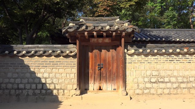 Tourist at a traditional stone fence with a gate in the Changdeokgung Palace. Seoul