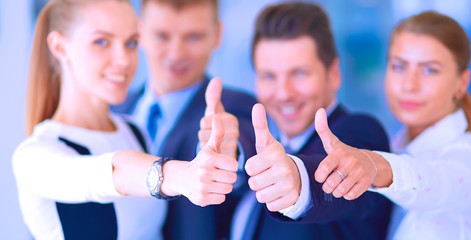 Happy business team showing thumbs up in office