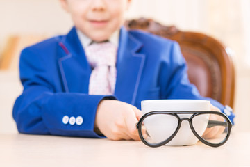Schoolboy with cup and glasses.