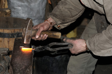Blacksmith forges a red-hot metal hammer