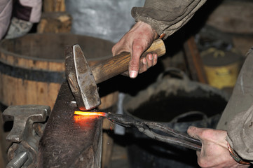 Blacksmith forges a red-hot metal hammer
