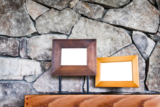 Stone fireplace wall close up with two empty picture frames on wood mantle
