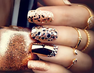 Fotobehang Nagelstudio Heldere manicure in gouden vakantiestijl met edelstenen en glitters. Trendy accessoires